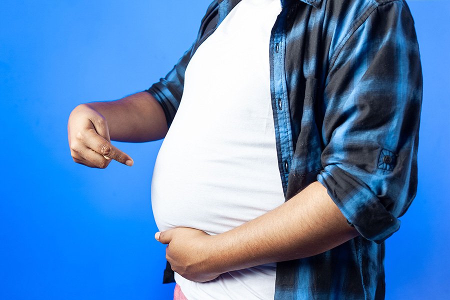 رجل يظهر بطنه البارز على خلفية زرقاء